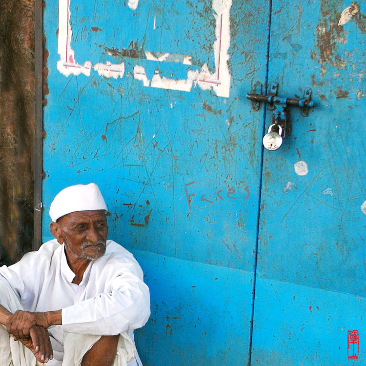 Man sitting in front of blue door